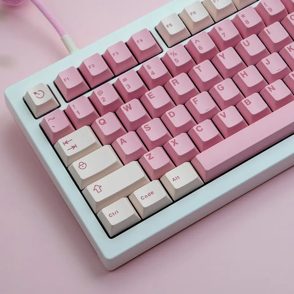 A close-up image of a white mechanical keyboard with pink keycaps. The keycaps feature a delicate rough surface and are compatible with various keyboard layouts.
