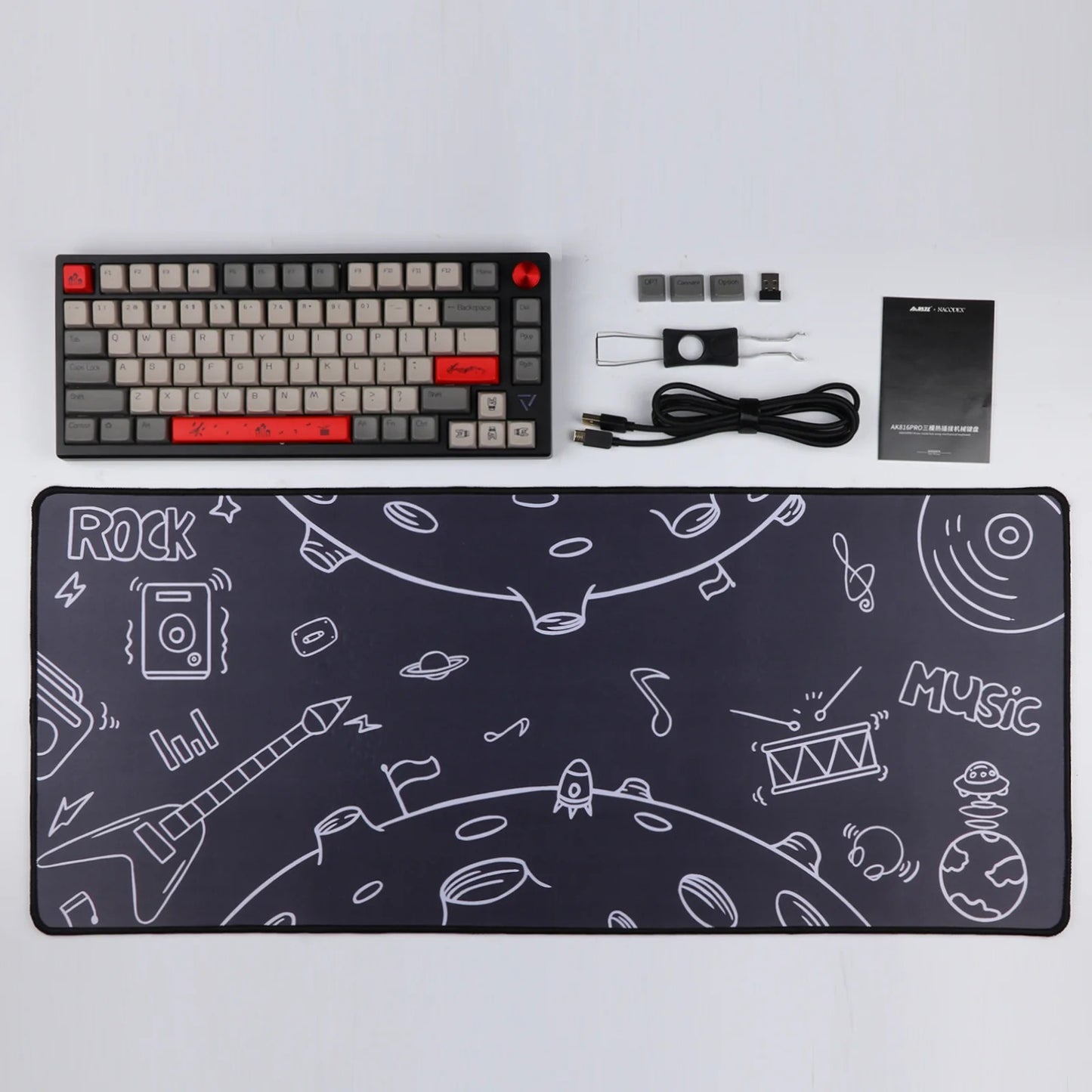 A top-down view of the Ajazz AK816 Pro mechanical keyboard, along with a matching mouse pad featuring a space-themed design with musical instruments. Other accessories included are a USB-C cable, keycap puller, and switch puller.