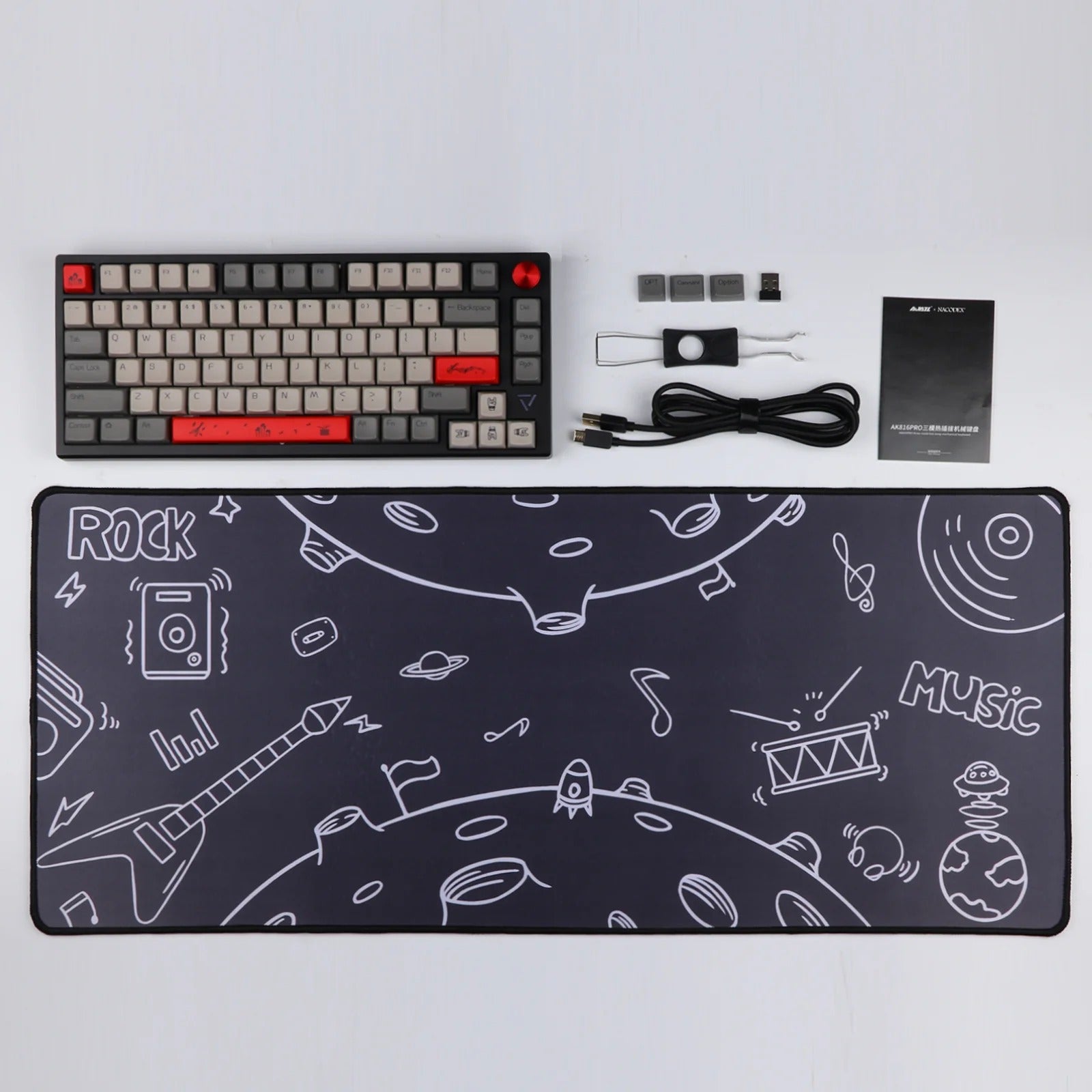 A top-down view of the Ajazz AK816 Pro mechanical keyboard, along with a matching mouse pad featuring a space-themed design with musical instruments. Other accessories included are a USB-C cable, keycap puller, and switch puller.